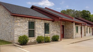 A two-story building with a brick facade, green shutters, and a red roof. - Texas Music City is a 5-minute walk from this 2 bedroom apartment (Lindale)