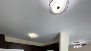 A modern kitchen with dark cabinets, a white refrigerator, a microwave, and a dining area with a wooden table and chairs. - Texas Music City is a 5-minute walk from this 2 bedroom apartment (Lindale)