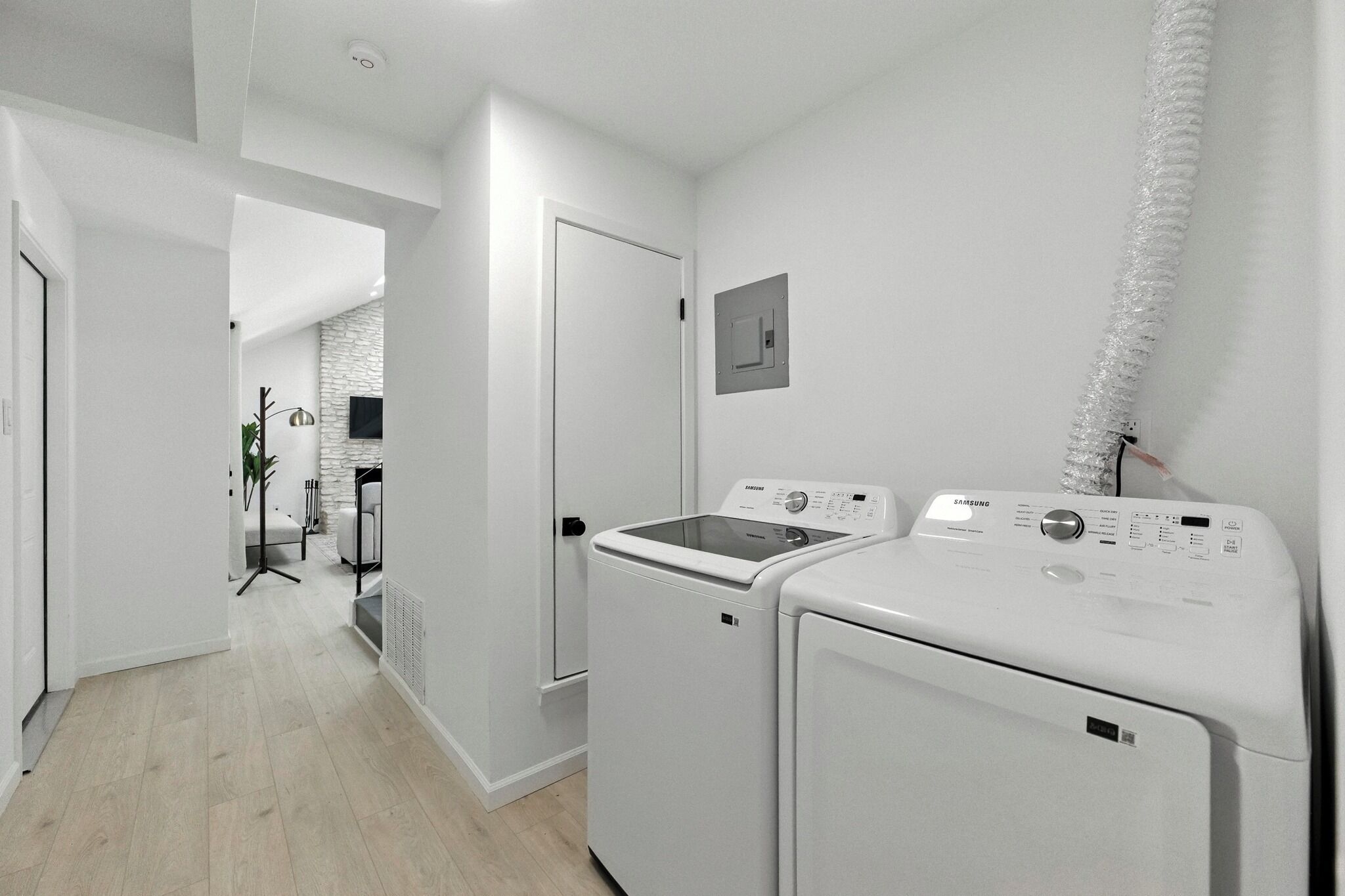 A laundry room with two white washing machines, a dryer, and a small wall-mounted heater.