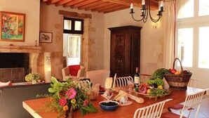 A dining area with a wooden table set for a meal, a fireplace, and a chandelier.