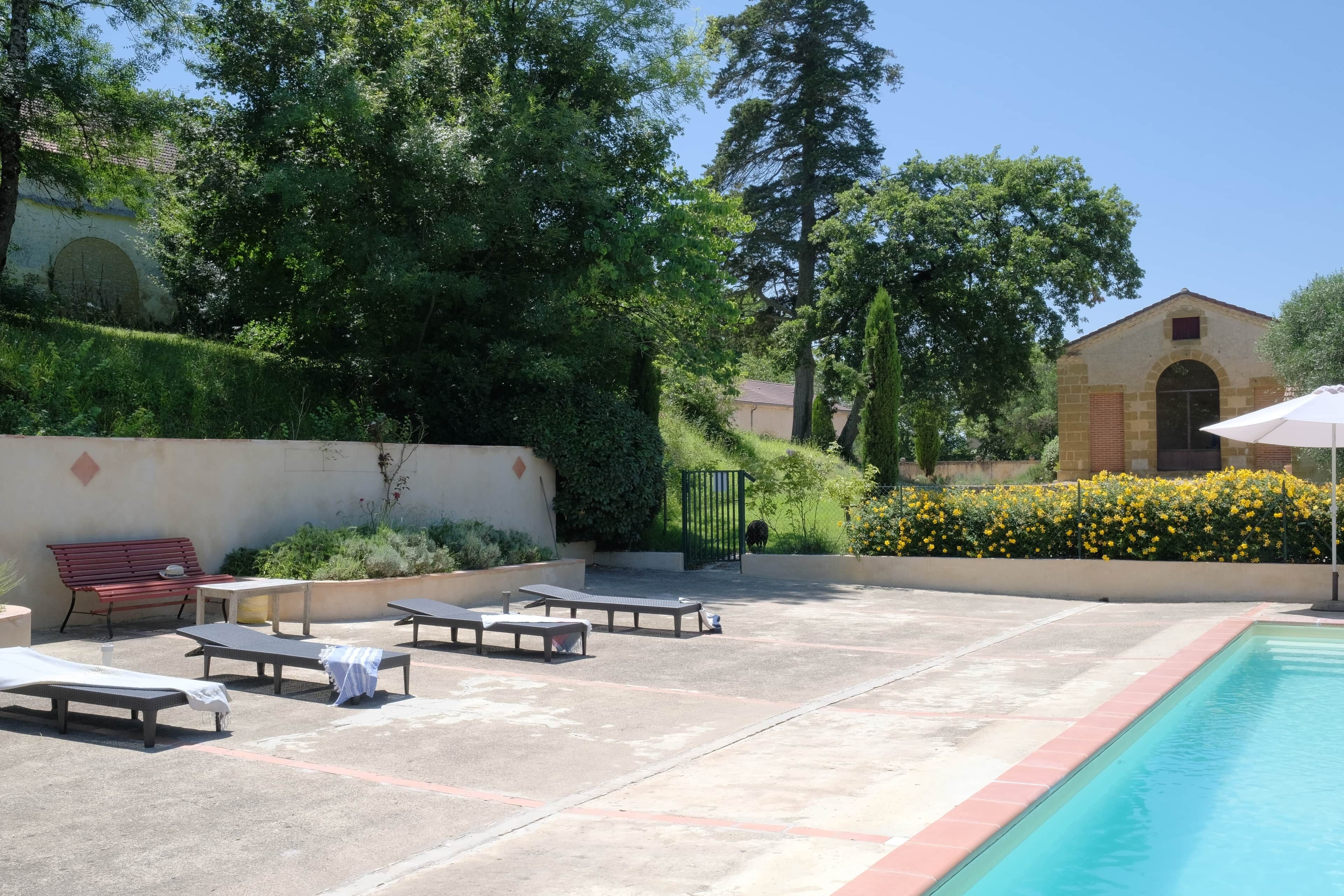 A pool area with lounge chairs, a bench, and a building in the background.