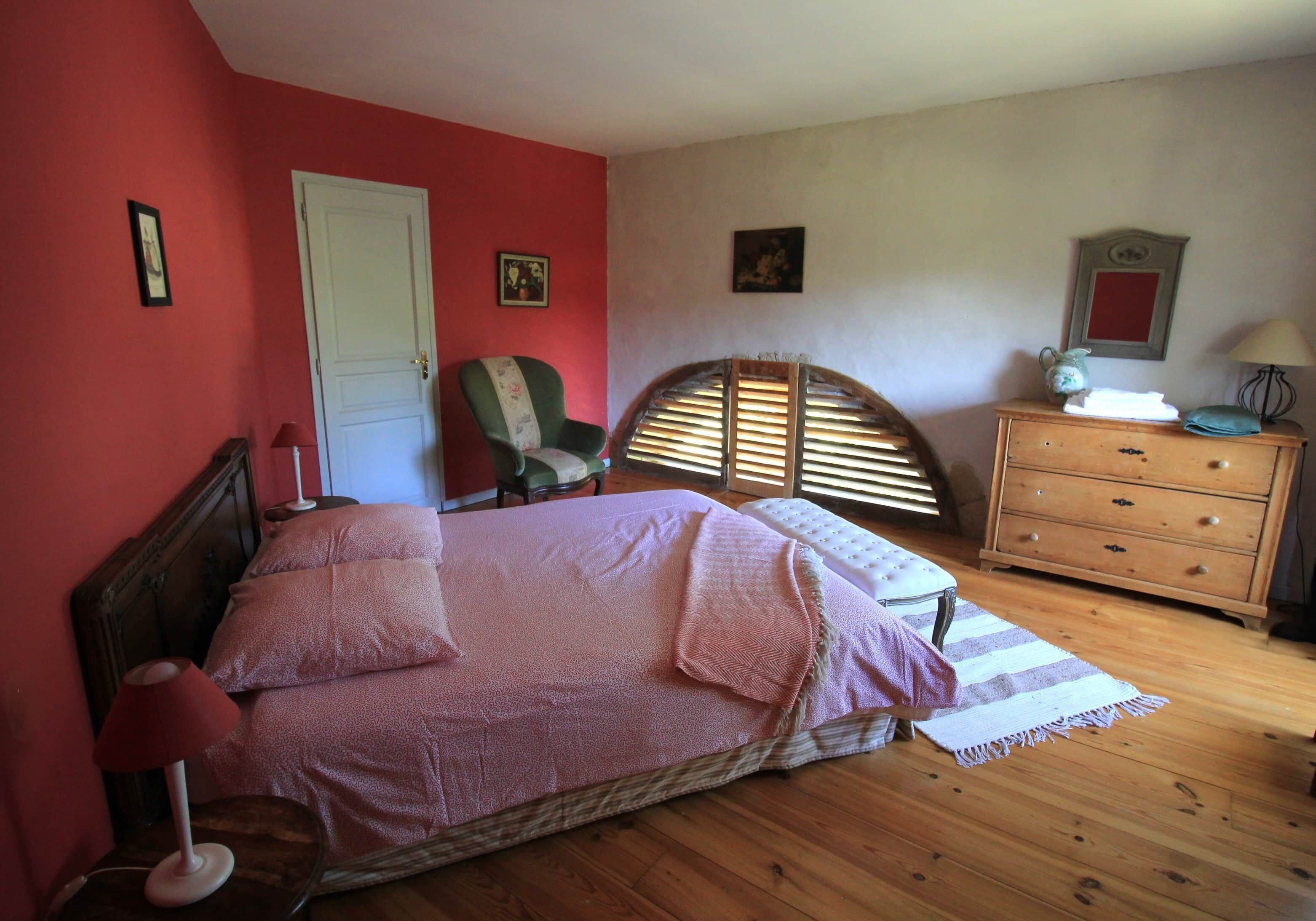 Un dormitorio con una cama, una silla, un aparador y una puerta.