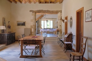 A spacious dining area with a wooden table and chairs, a chandelier, and a view of the dining room through an archway.