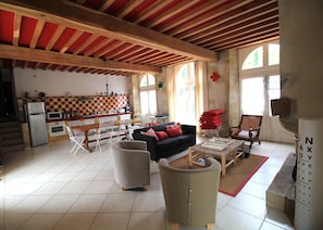 A spacious living area with a kitchen, a sofa, a dining table, and a red and white checkered wall.