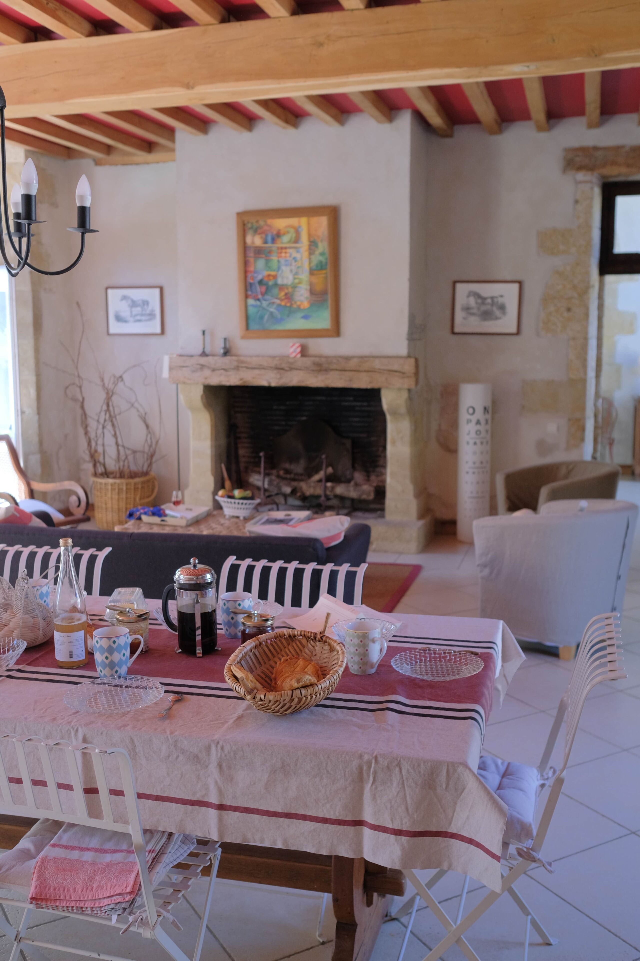 A dining area with a table set for four, a fireplace, and a painting on the wall.