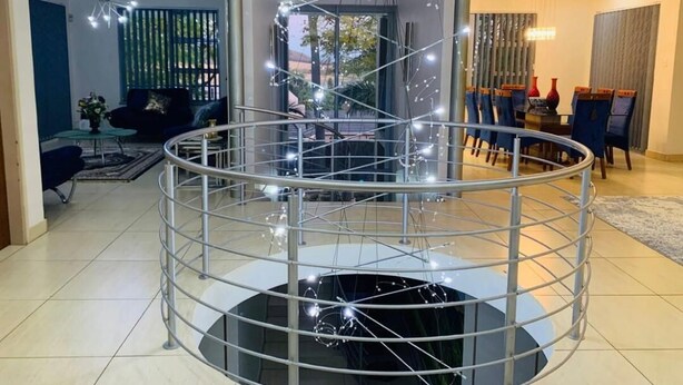 Un intérieur moderne avec un escalier en colimaçon central, un coin repas comprenant des chaises et une table, et un salon avec un canapé et des objets décoratifs.