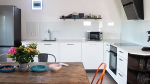 Een moderne keuken met witte kasten, een houten eettafel en een rode stoel.