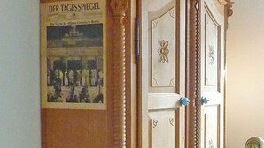Een kamer met een houten garderobe en een poster aan de muur.