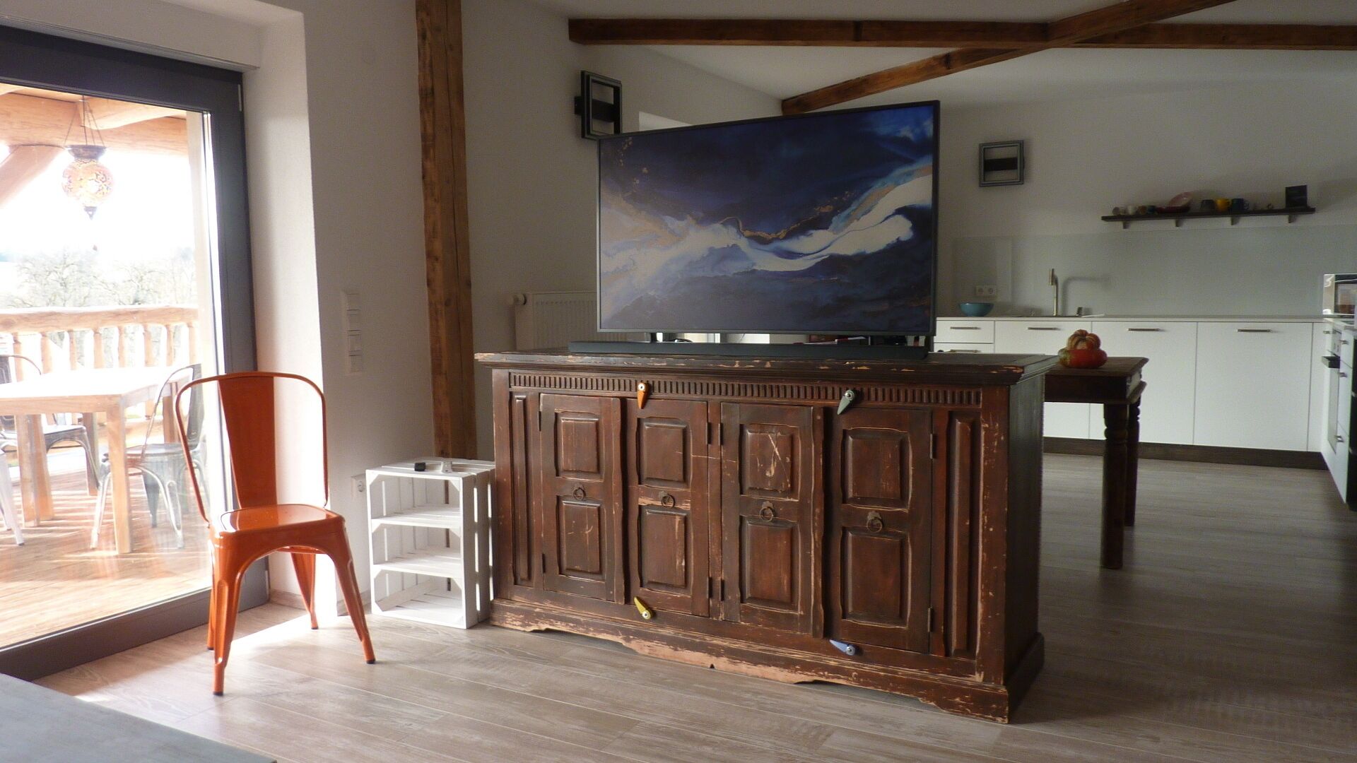 Un salon avec un meuble en bois, un téléviseur et un fauteuil.