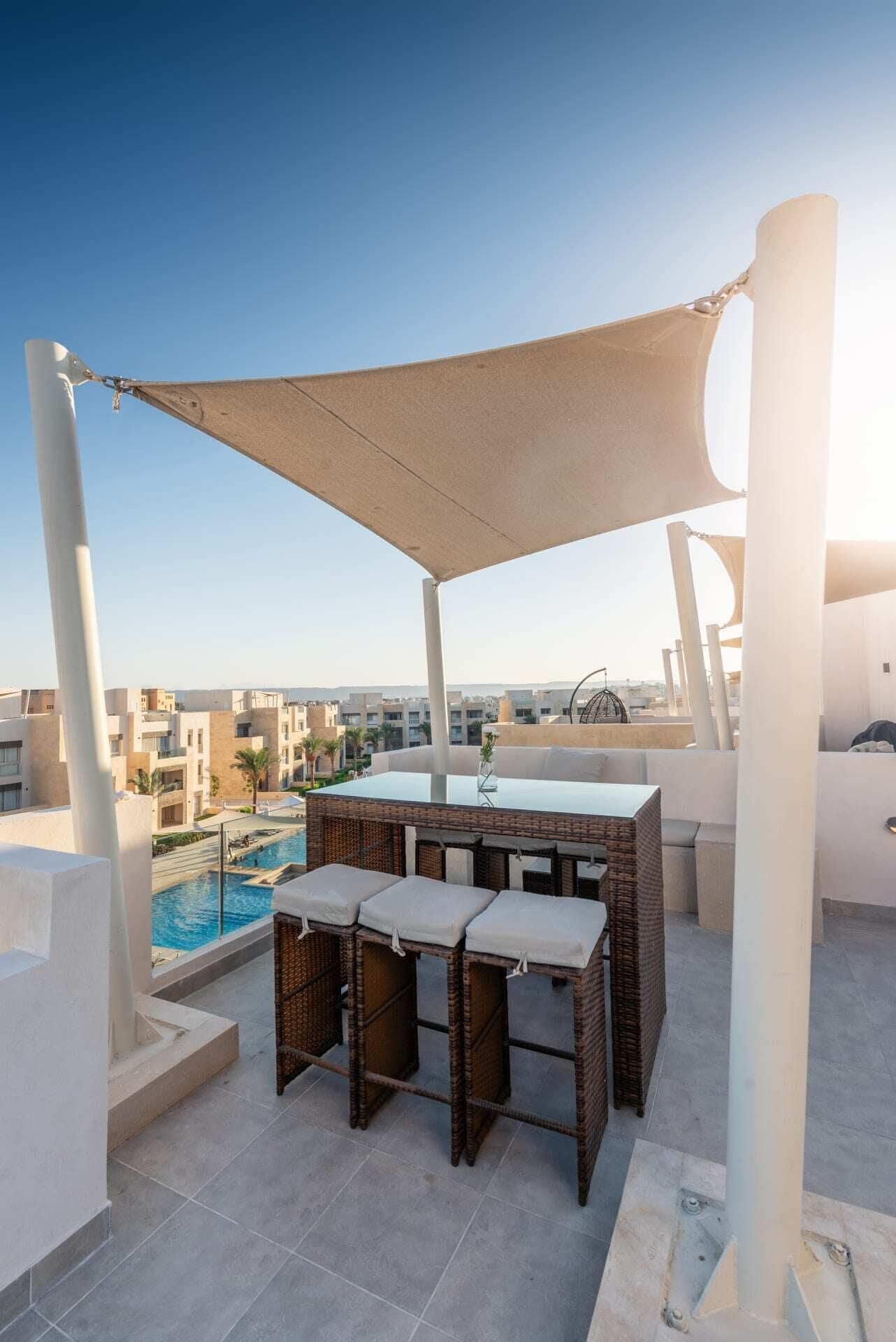 Terraza en la azotea con piscina, mobiliario exterior y vista panorámica de la ciudad.