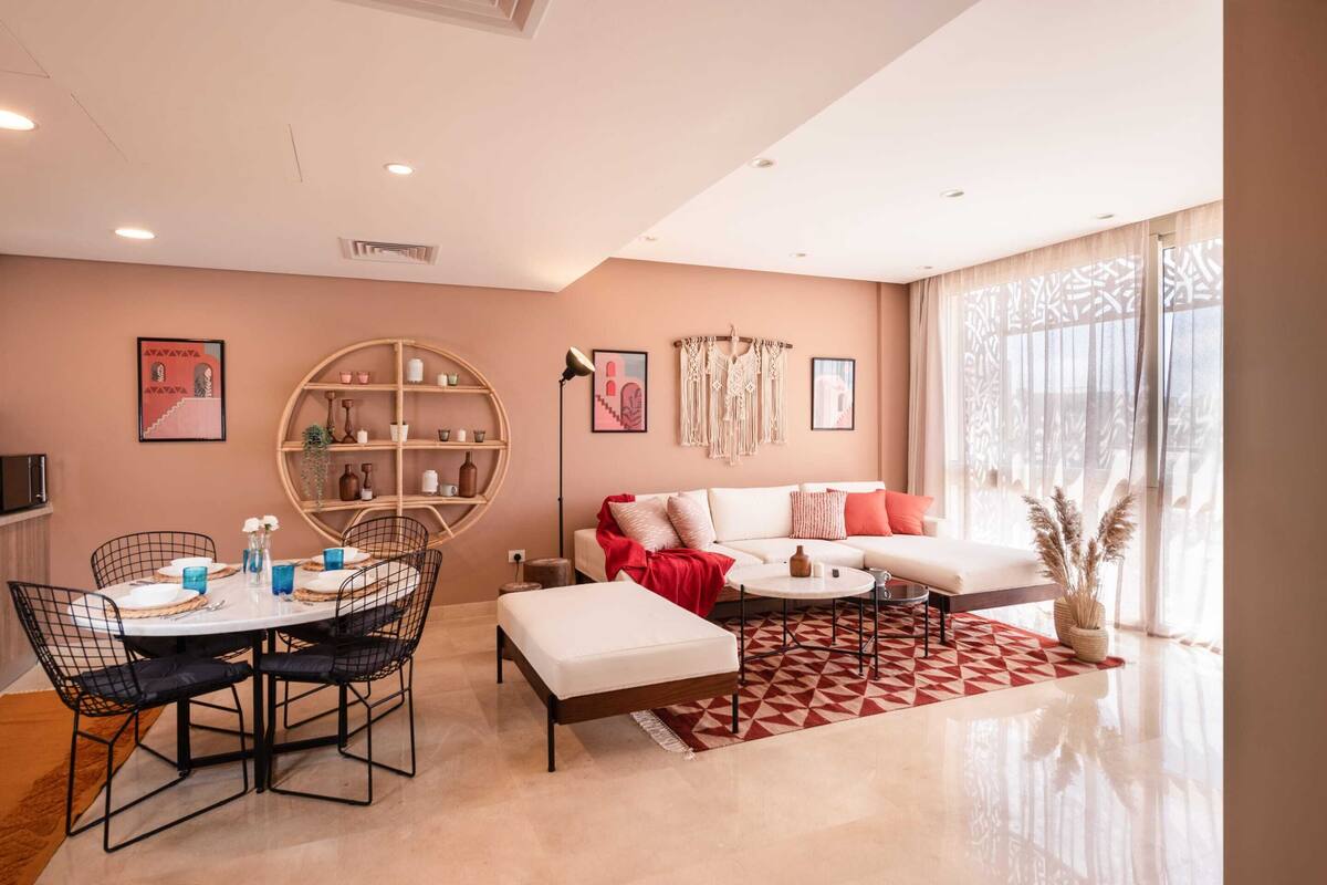 A modern living room with a white sofa, a dining table with chairs, and a coffee table.
