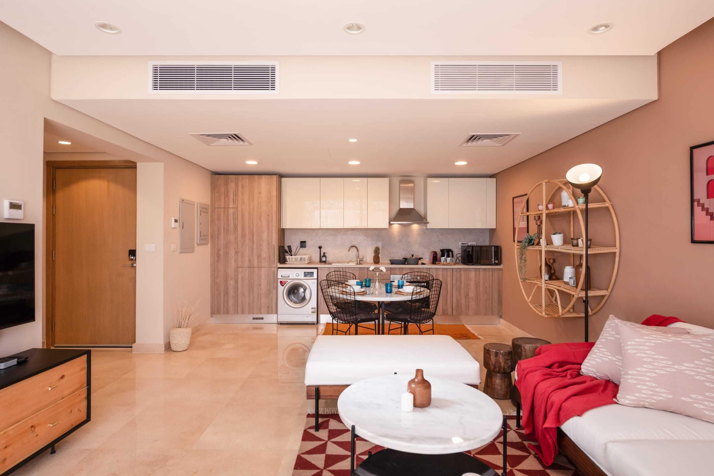Un appartement moderne comprenant un salon, un coin repas et une cuisine. Il est équipé d’un canapé, d’une table à manger et d’un téléviseur.