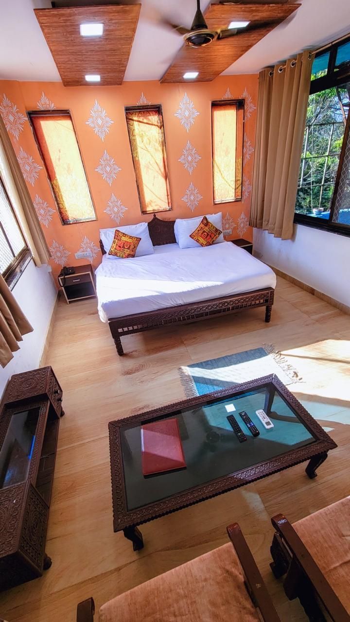 A bedroom with a large bed, a glass coffee table, and a view of the outdoors.