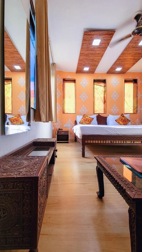 A hotel room with two beds, a wooden floor, a ceiling fan, and a large window with curtains.