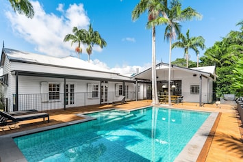 Spacious magnesium pool with sun lounges, surrounded by tropical palms and directly adjoining the outdoor dining and BBQ area.