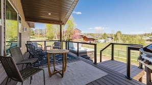Eine überdachte Terrasse im Freien mit Grill, Sitzgelegenheit und Blick auf die umliegende Landschaft.