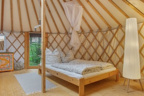 A single bed with a canopy in a tent-style room with a view of greenery outside. - Cozy 28 m² yurt with stargazing view, barbecue area, and separate bathroom (Wald)