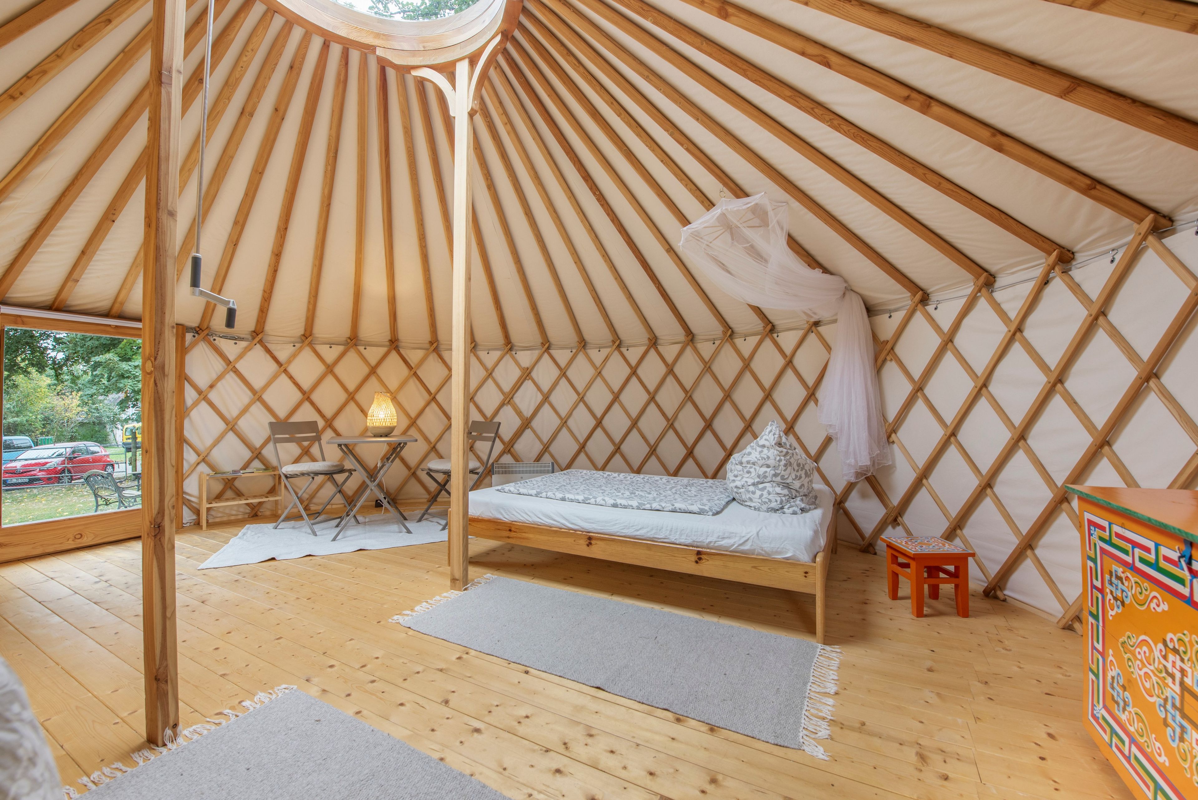 A yurt interior with a bed, seating area, and a view through the entrance.