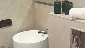 A bathroom with a white sink, a wooden cabinet, a mirror, and a shower.