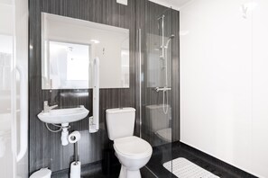 A modern bathroom with a glass shower enclosure, a white sink, and a toilet. - Rivers Hotel (Gateshead)