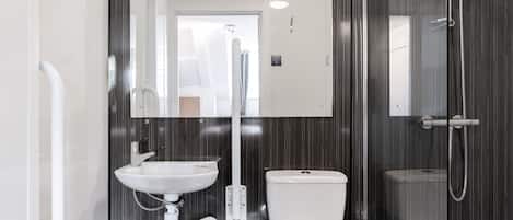 A modern bathroom with a white sink, toilet, and shower.
