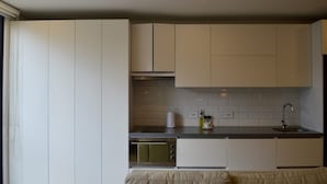 A modern kitchen with white cabinets, a stainless steel oven, and a black countertop. - NOK Cozy Studio in Parque Virrey (Bogotá)