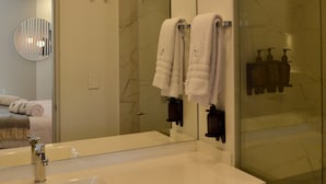 A modern bathroom with a large mirror, a sink, and a glass shower enclosure. - NOK Cozy Studio in Parque Virrey (Bogotá)