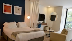 A modern hotel room with a large bed, a sofa, a TV, and a balcony with a view. - NOK Cozy Studio in Parque Virrey (Bogotá)