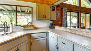 A kitchen with wooden cabinets, a granite countertop, and a coffee maker. - Scenic Riverfront Escape w/ Sauna in Junction City (Junction City)