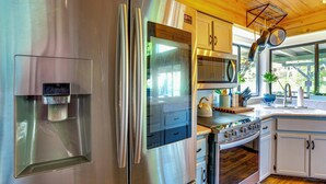 A modern kitchen with stainless steel appliances, a water dispenser, a microwave, and a stove. - Scenic Riverfront Escape w/ Sauna in Junction City (Junction City)