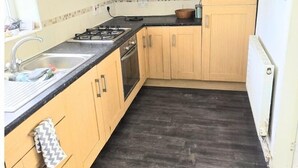 Una cocina con armarios de madera, encimera negra, estufa a gas y campana extractora negra.
