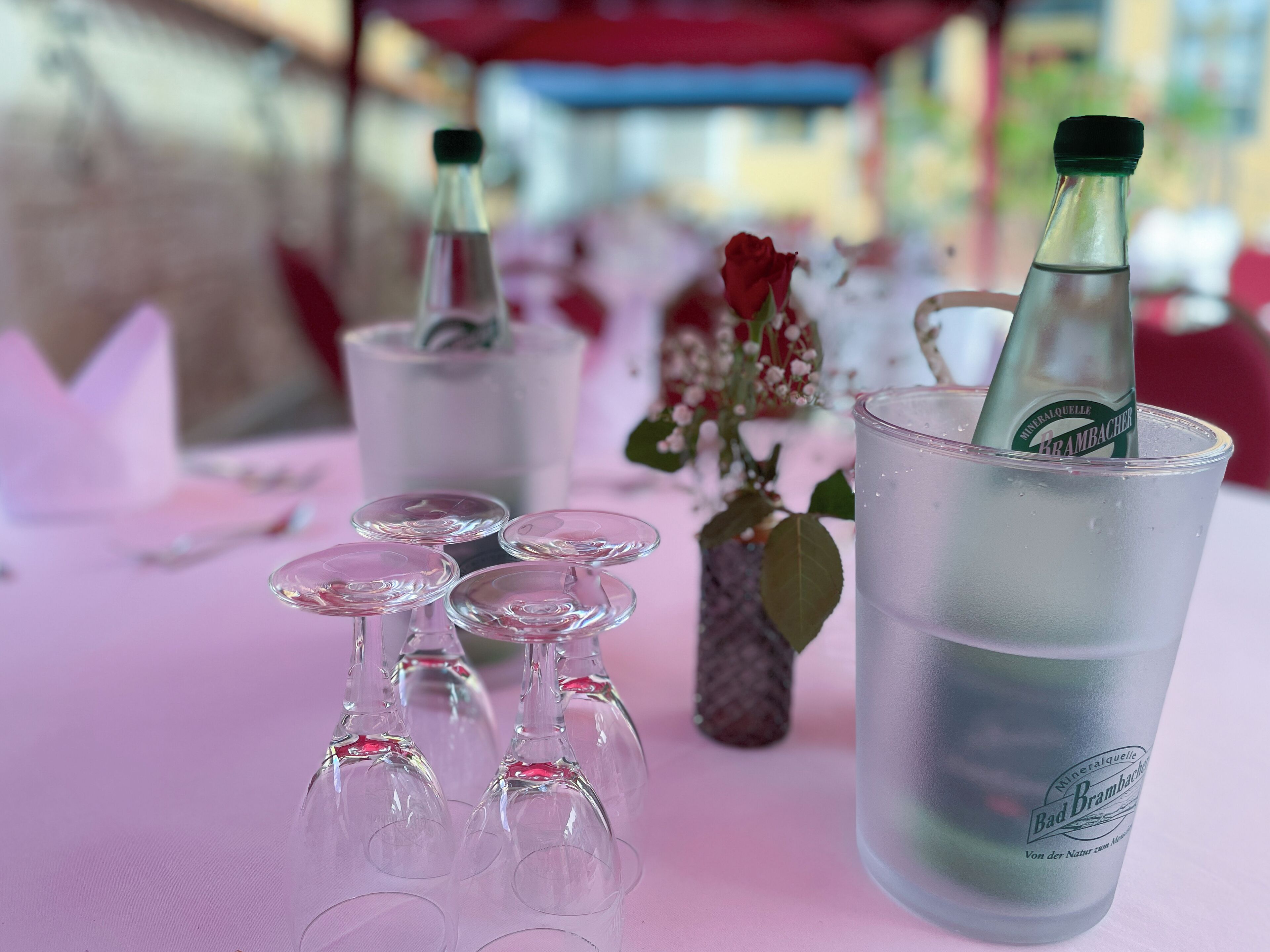 A table with a frosted glass cup, a bottle, and several empty glasses.