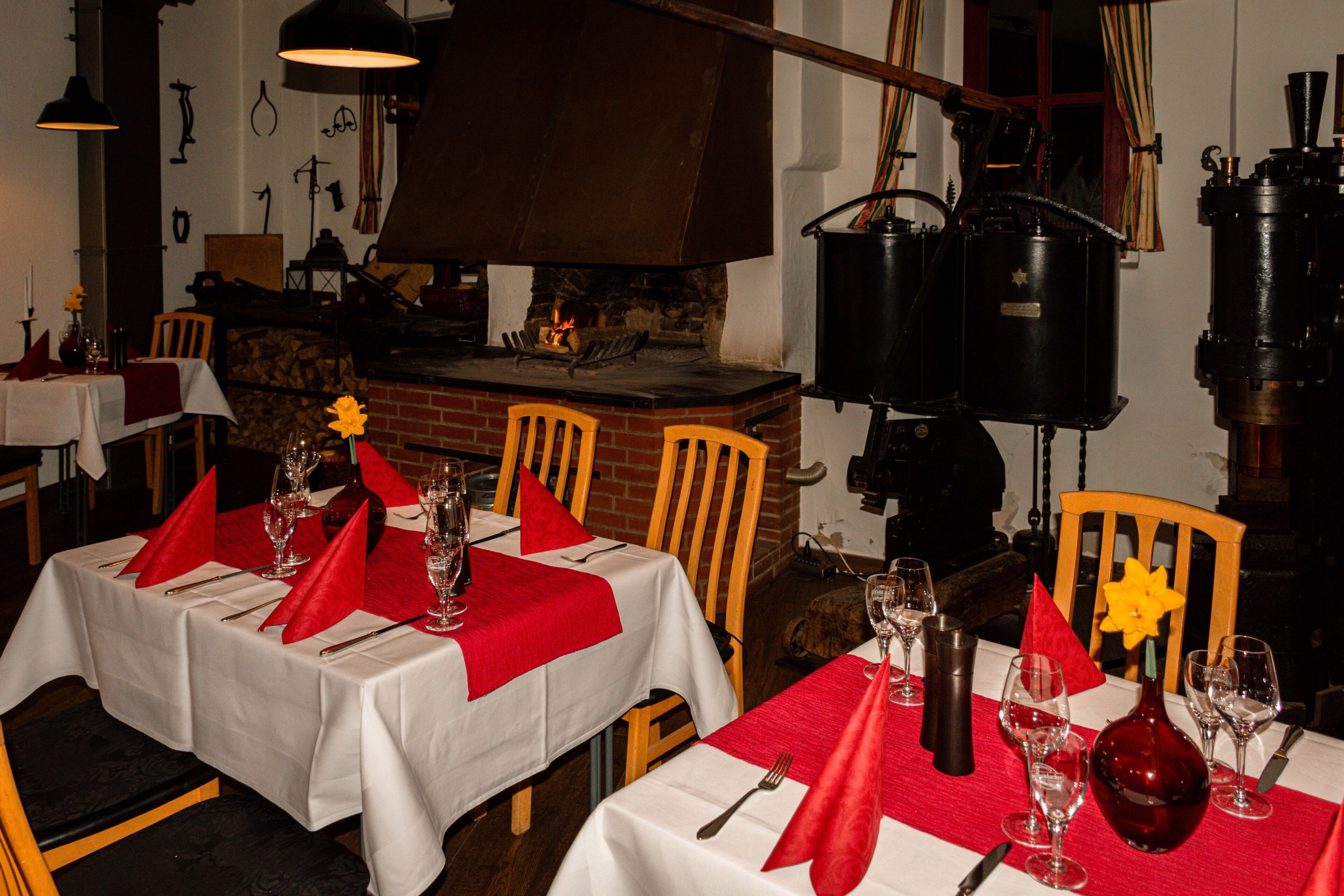 A restaurant with tables set for dining, a brick fireplace, and vintage-style lighting fixtures.