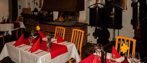 A restaurant with tables set for dining, a brick fireplace, and vintage-style lighting fixtures.