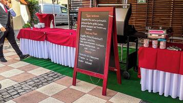 Un tablero de menú con opciones de comida, una mesa con mantel rojo y un paraguas verde.