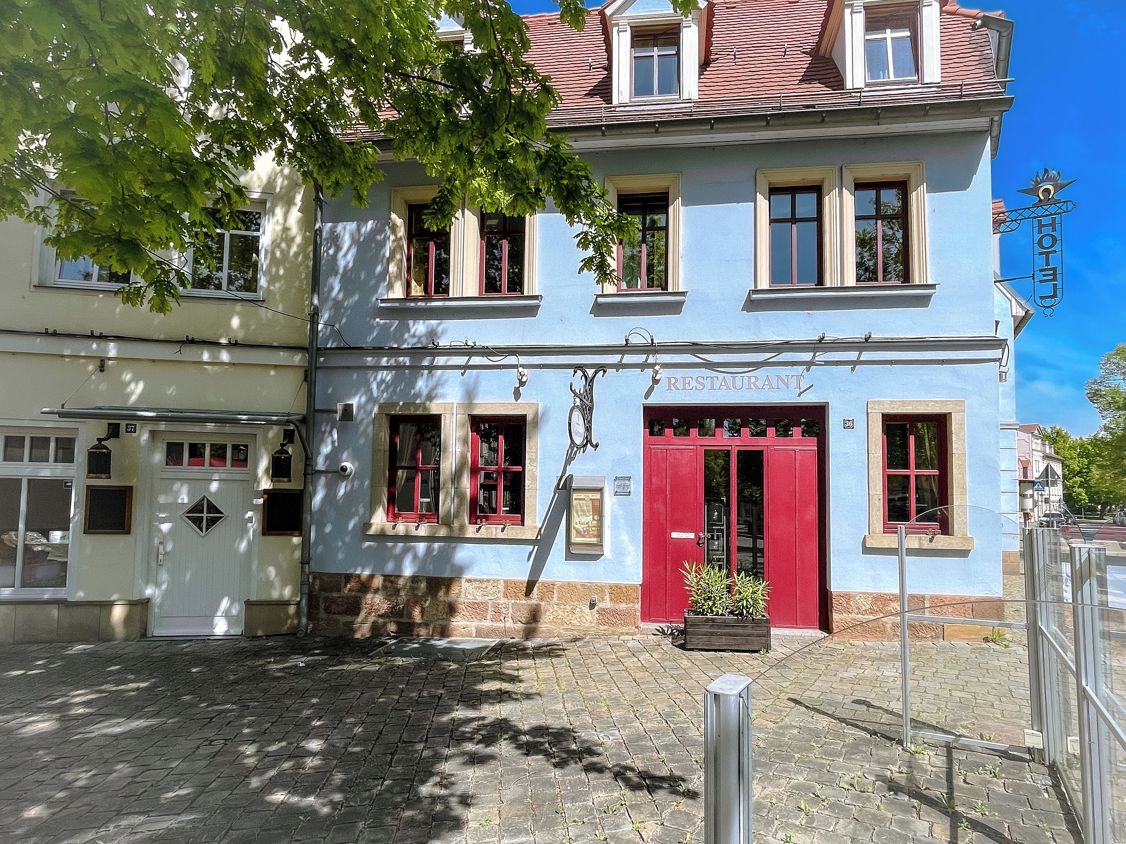 A two-story building with a red door and windows, labeled 'RESTAURANT' above the entrance.