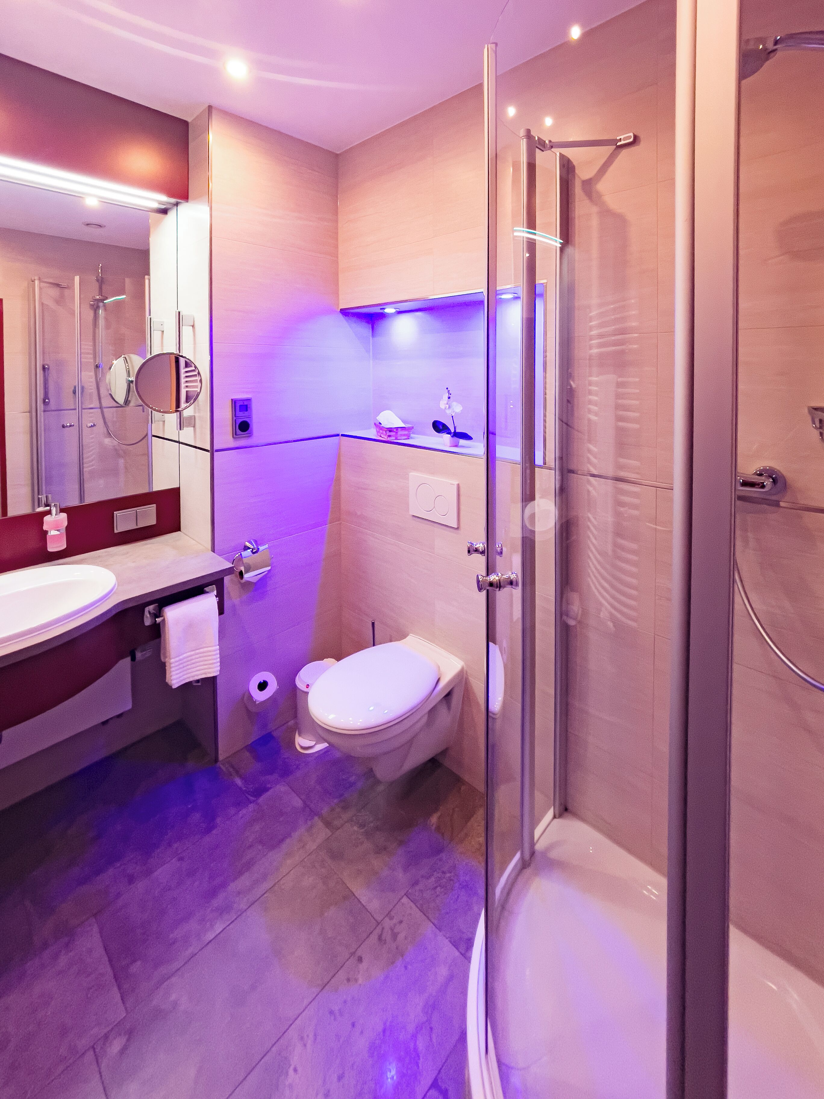 Un baño moderno con cabina de ducha de vidrio, inodoro y lavamanos con espejo.