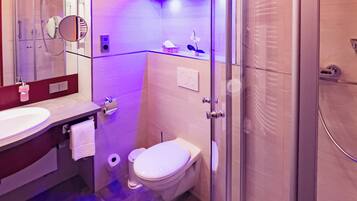 Un baño moderno con cabina de ducha de vidrio, inodoro y lavamanos con espejo.