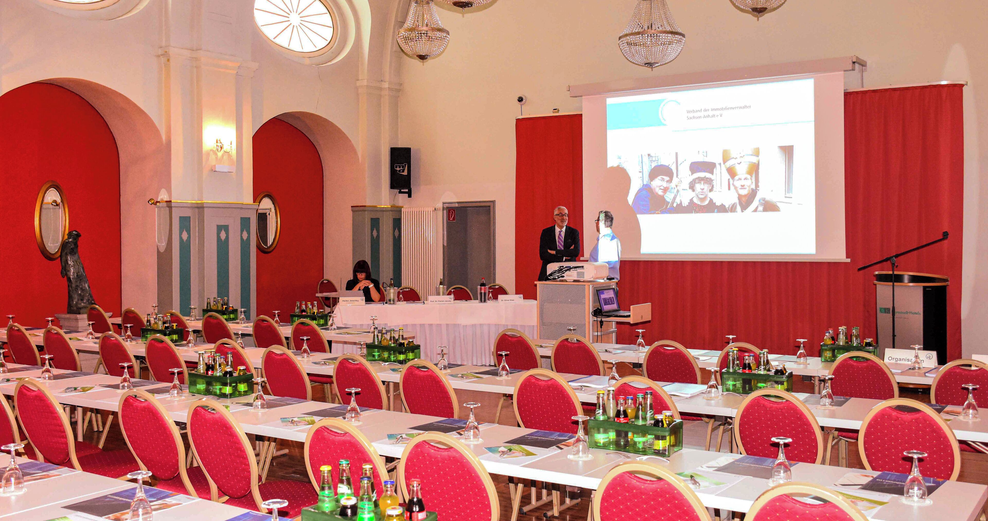 A conference room with tables, chairs, and a presentation screen.