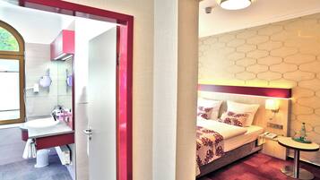 Une chambre d’hôtel comprenant un lit, une table de chevet et une salle de bain avec un lavabo et un miroir.