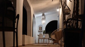 Un couloir avec un escalier, deux chaises, une table et un luminaire suspendu.