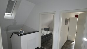 Een compacte kamer met een bed, een kleine kitchenette en een raam.