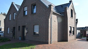 Een gebouw van baksteen met een puntige dakschild en een opvallende ingang, met een geplaveid oprit.