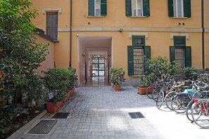 A courtyard with potted plants, a bike rack, and a building entrance.