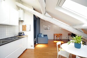A modern kitchen with white cabinets, a gas stove, and a dining area with a round table and chairs.