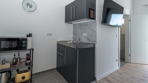 A compact kitchen with a microwave, toaster, and a small refrigerator. - LiT LiVING: Luxus | Box SprIng | Kitchen | Parking (Altenstadt)