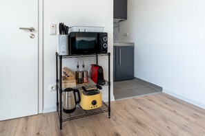A kitchen with a microwave, toaster, and coffee maker on a wire shelf.