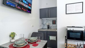 A modern kitchen with a TV, cabinets, and a microwave. - LiT LiVING: Luxus | Box SprIng | Kitchen | Parking (Altenstadt)