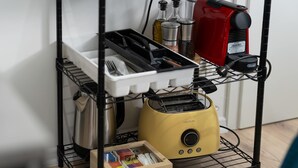 A kitchen area with a yellow toaster, a coffee maker, and a drawer with various items. - LiT LiVING: Luxus | Box SprIng | Kitchen | Parking (Altenstadt)