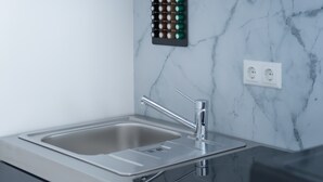 Une cuisine moderne dotée d’un évier en acier inoxydable, d’un dosseret en marbre et d’un porte-épices noir.